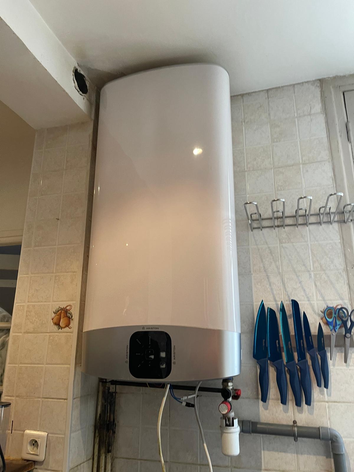 Chauffe-eau Ariston blanc fixé sur le mur de la même cuisine carrelée